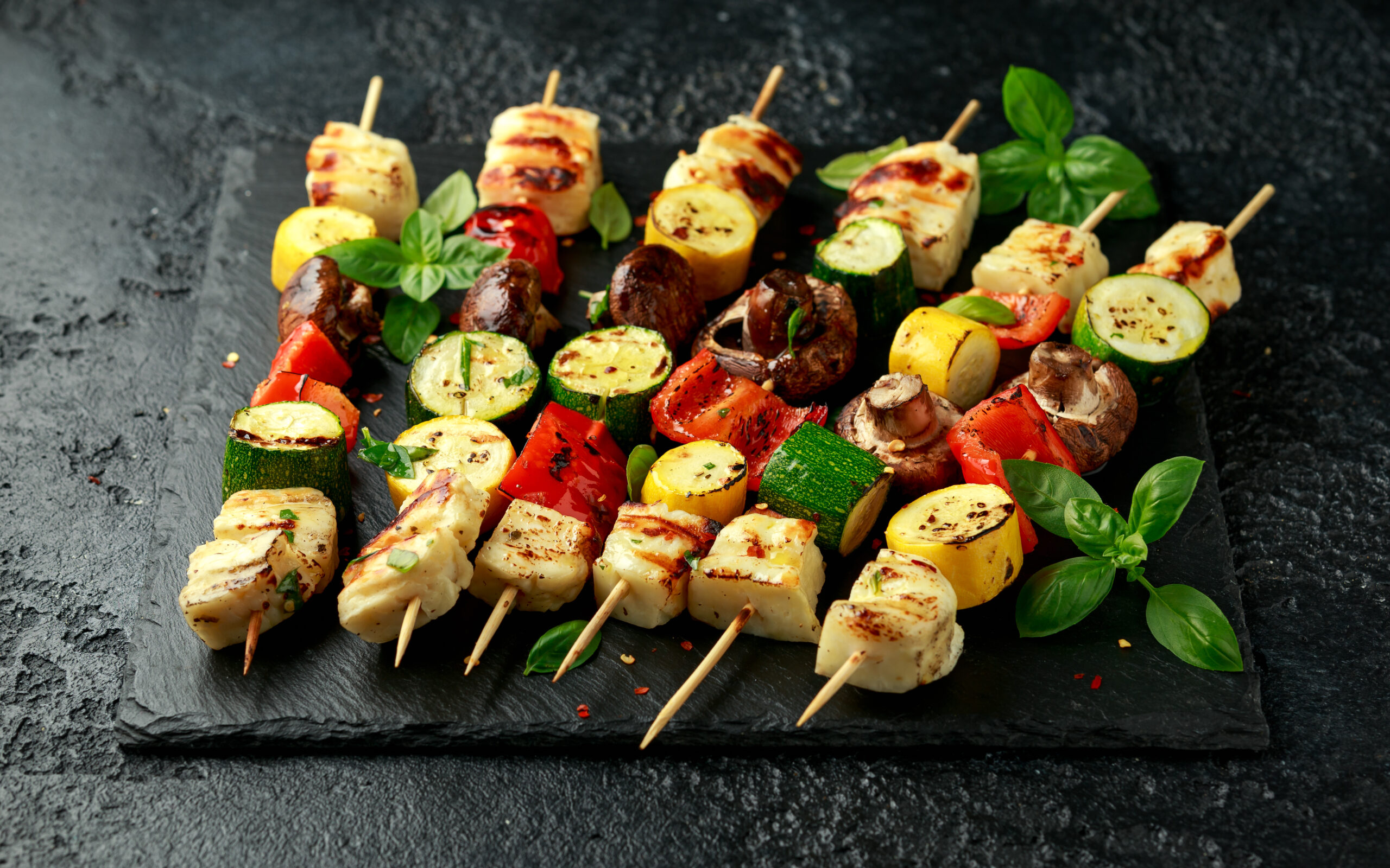 Grilled Halloumi cheese skewers with vegetables on rustic stone board